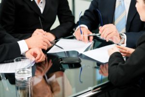 meeting at conference table showing papers in hands